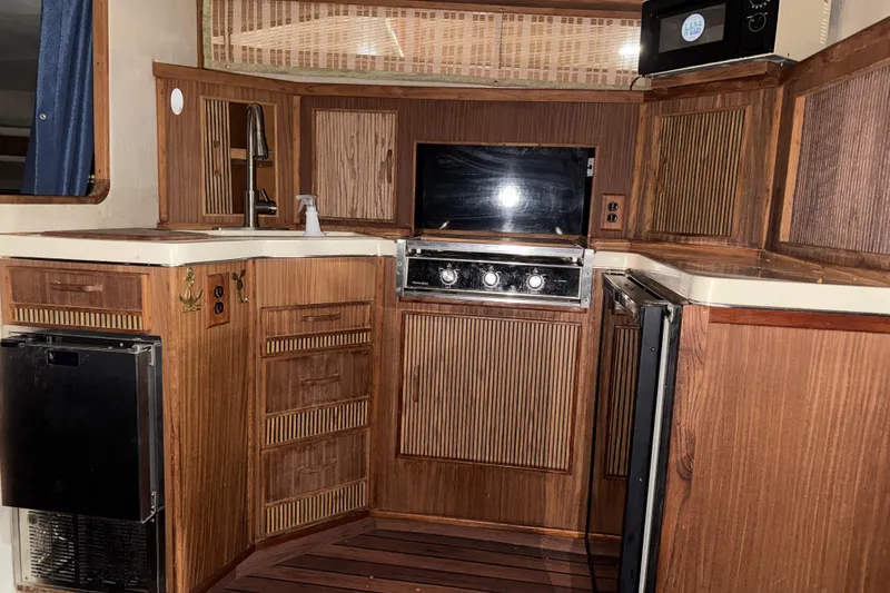 Slide: The Image of 1986 Sea Ray 340 Express Cruiser kitchen with wood cabinetry and appliances. - 15