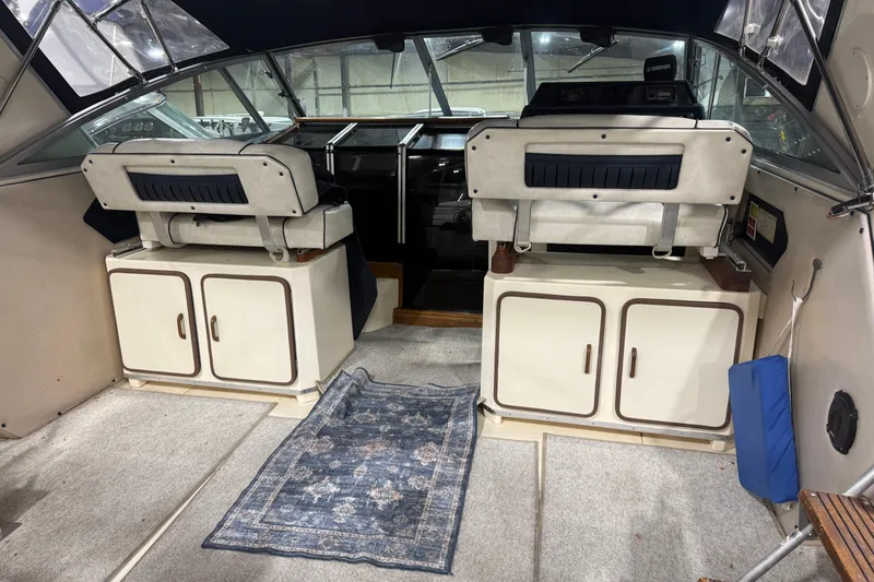 Slide: The Image of 1986 Sea Ray 340 Express Cruiser interior with helm seats and storage cabinets. - 4