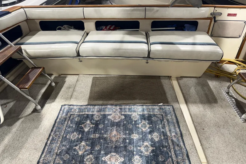 Slide: The Image of 1986 Sea Ray 340 Express Cruiser interior with cushioned seating and patterned rug. - 7