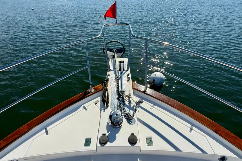 Slide: The Image of Bow view of 1997 Sabreline 47 yacht with red flag on calm water. - 16