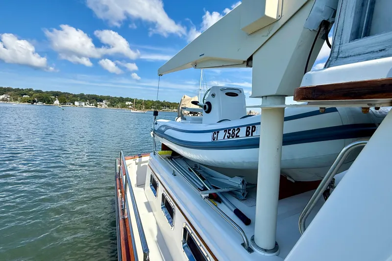 Slide: The Image of 1997 Sabre Sabreline 47 yacht with a small boat on deck, docked by a scenic shoreline. - 26
