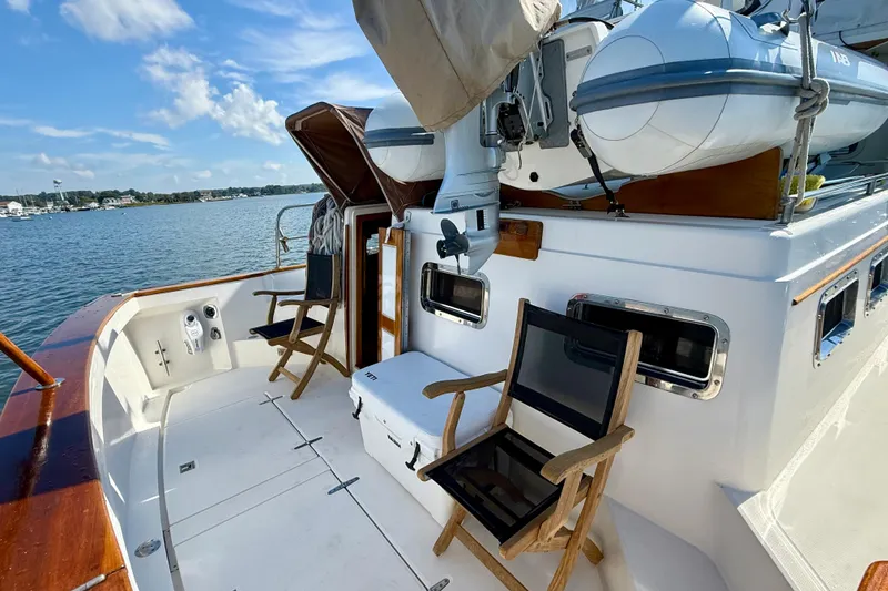 Slide: The Image of 1997 Sabre Sabreline 47 yacht deck with chairs, cooler, and inflatable boat, overlooking serene waters. - 27