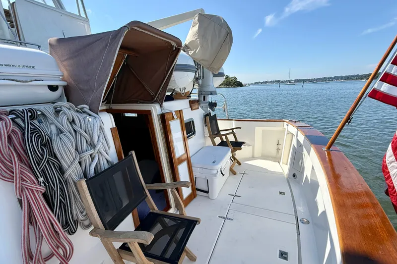 Slide: The Image of 1997 Sabre Sabreline 47 yacht deck with chairs, ropes, and American flag on calm water. - 28