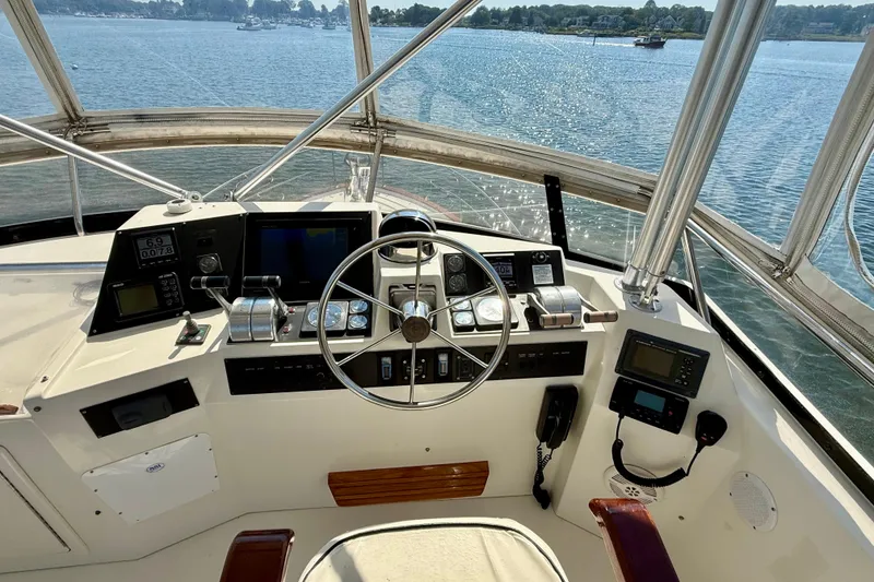 Slide: The Image of 1997 Sabre Sabreline 47 yacht helm with navigation instruments and steering wheel, overlooking calm waters. - 38