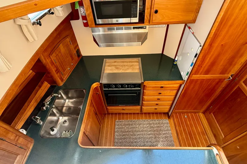 Slide: The Image of 1997 Sabre Sabreline 47 yacht kitchen with wood cabinetry, dual sink, and modern appliances. - 50