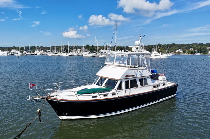 Slide: The Image of 1997 Sabre Sabreline 47 yacht anchored in a scenic marina with sailboats. - 2