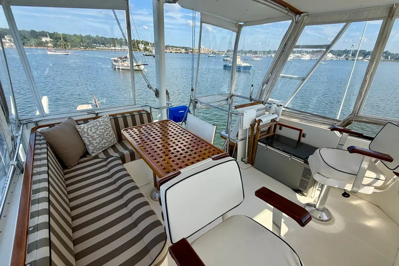 Slide: The Image of 1997 Sabre Sabreline 47 yacht interior with striped seating, wooden table, and scenic water view. - 32