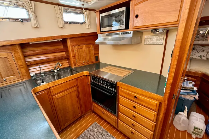 Slide: The Image of 1997 Sabre Sabreline 47 yacht kitchen with wood cabinetry, stove, and microwave. - 48