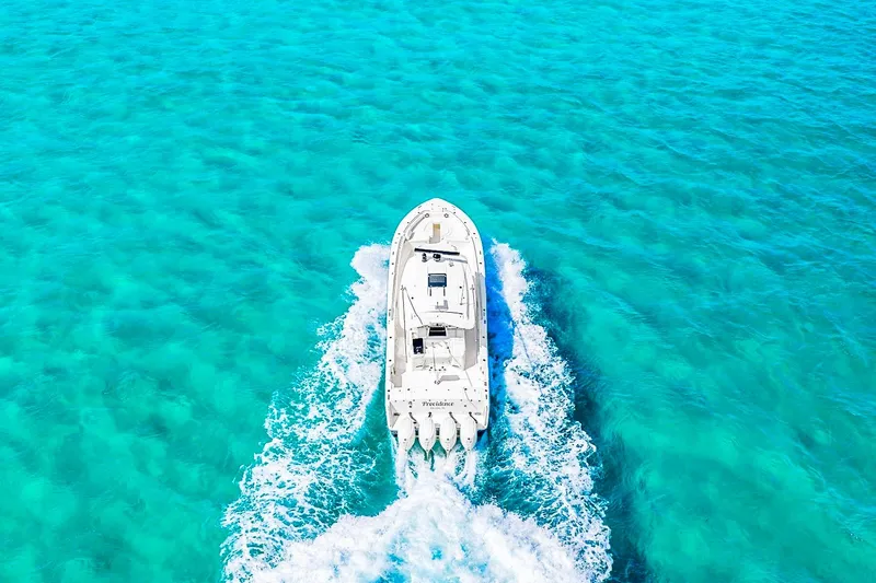 Slide: The Image of Aerial view of 2025 Grady-White Canyon 456 boat cruising in clear turquoise waters. - 11