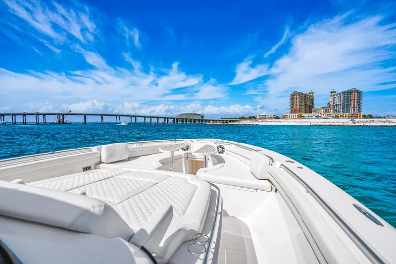 Slide: The Image of 2025 Grady-White Canyon 456 boat cruising near a coastal cityscape and bridge. - 41
