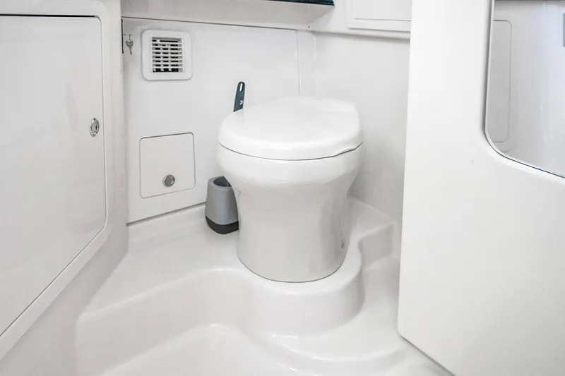 Slide: The Image of 2025 Grady-White Canyon 456 boat bathroom with modern white toilet and compact design. - 54