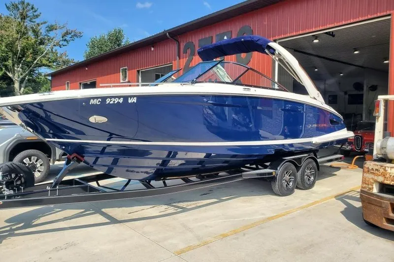 The Image of 2021 Regal 2800 Bowrider boat on trailer outside a red building. - 0