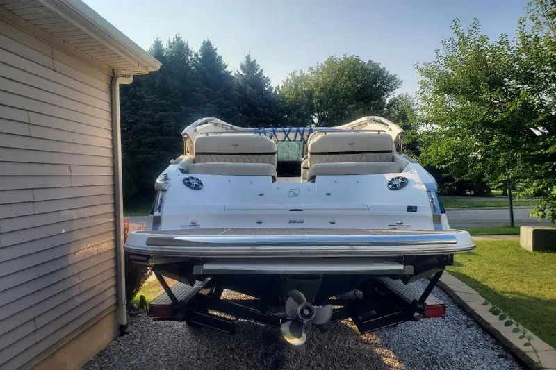 Slide: The Image of 2021 Regal 2800 Bowrider boat parked beside a house, surrounded by trees. - 6