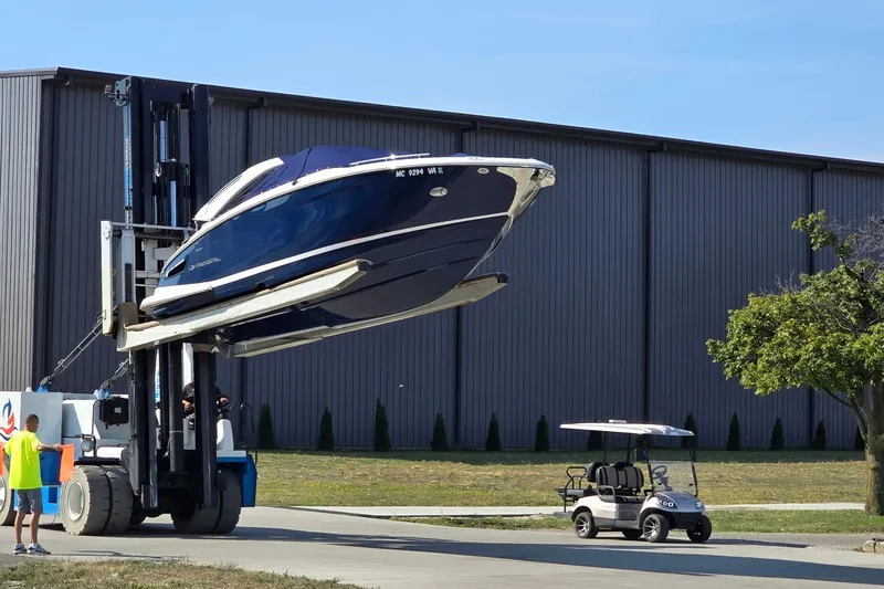 Slide: The Image of 2021 Regal 2800 Bowrider boat lifted by forklift near a golf cart. - 9