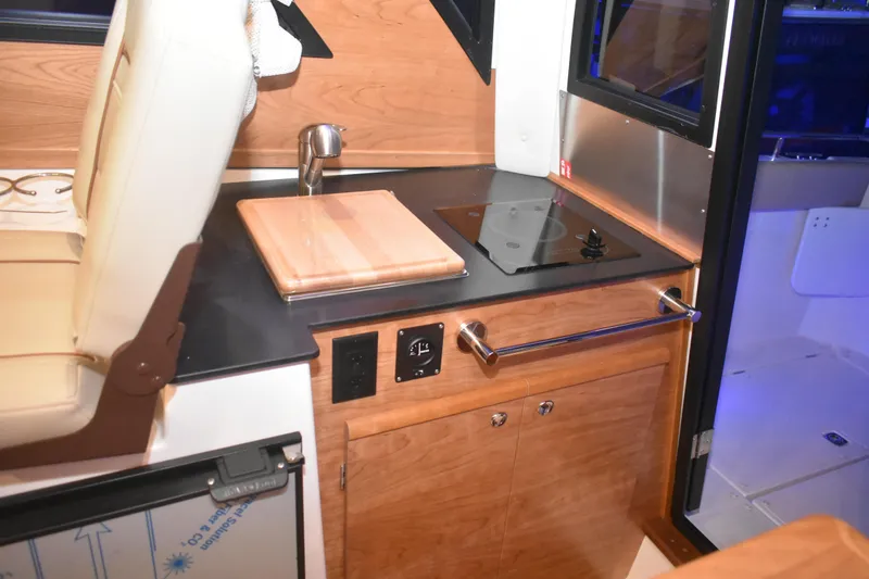 Slide: The Image of 2026 Cutwater C-248 Coupe interior kitchen with stove, sink, and wooden cabinetry. - 26