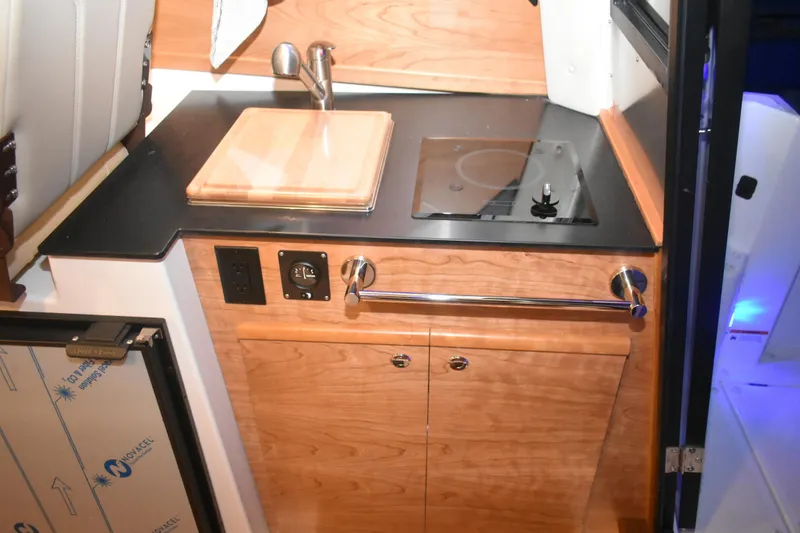 Slide: The Image of 2026 Cutwater C-248 Coupe interior kitchen with sink, stove, and wooden cabinetry. - 27