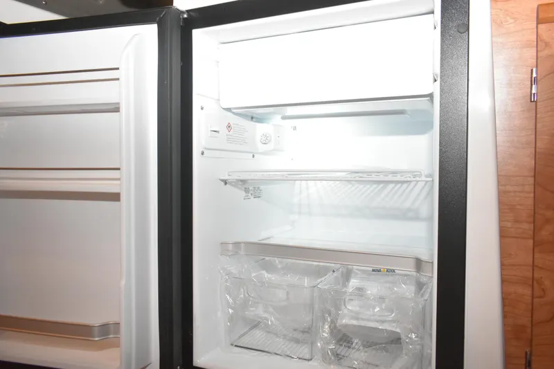 Slide: The Image of Open refrigerator inside 2026 Cutwater C-248 Coupe boat, showcasing shelves and storage compartments. - 29