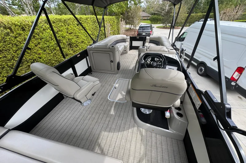 Slide: The Image of 2019 Barletta L25UCL pontoon boat interior with beige seating and steering console. - 7