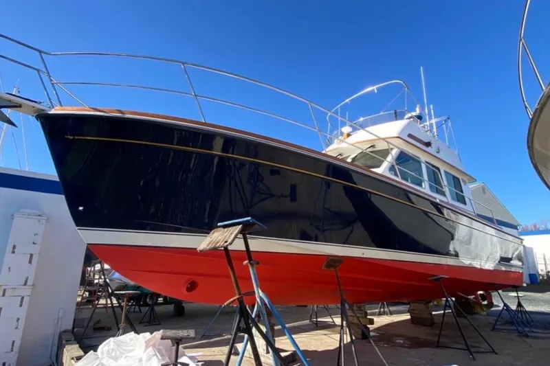 The Image of 2004 Sabre 42 Fly Bridge boat on stands, blue hull, red bottom, clear sky. - 0