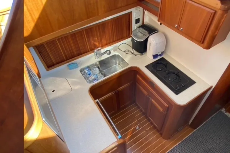 Slide: The Image of 2004 Sabre 42 Fly Bridge kitchen with stove, sink, and wooden cabinetry. - 10