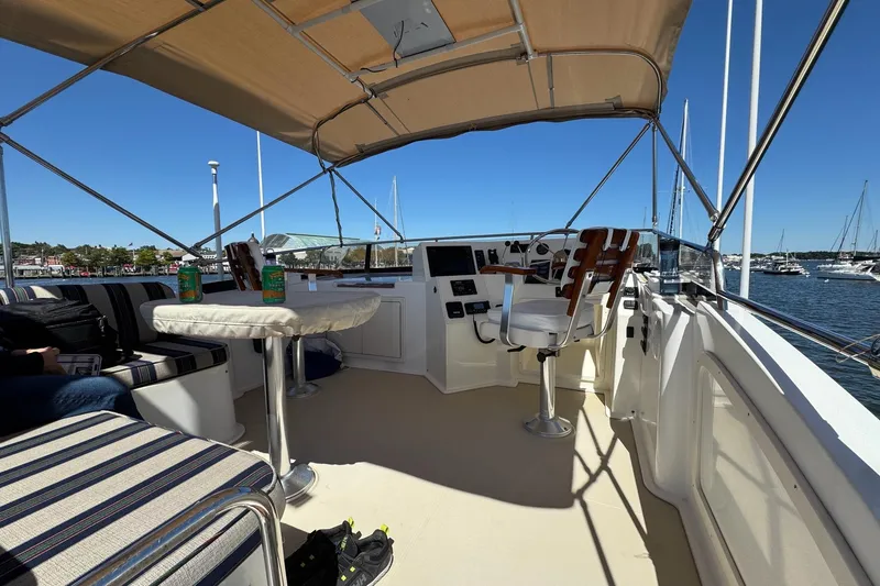 Slide: The Image of 2004 Sabre 42 Fly Bridge interior with seating, table, and helm, overlooking marina. - 4
