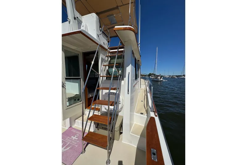 Slide: The Image of 2004 Sabre 42 Fly Bridge yacht with wooden stairs, docked in a marina under clear blue skies. - 5