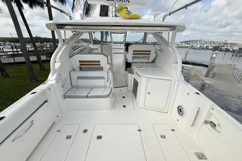 Slide: The Image of 2022 Pursuit DC 365 Dual Console boat interior at marina, showcasing seating and storage. - 4