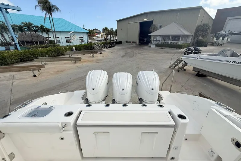 Slide: The Image of 2022 Pursuit DC 365 Dual Console boat with triple outboard engines at a marina. - 7
