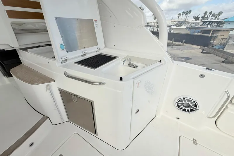 Slide: The Image of 2022 Pursuit DC 365 Dual Console boat kitchen area with sink and storage. - 9