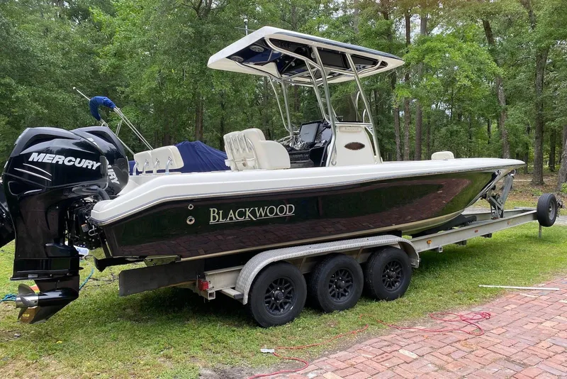 The Image of 2013 Blackwood 27 boat on trailer with Mercury engine, parked on grass. - 1