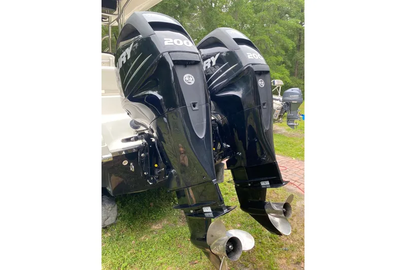 Slide: The Image of Twin Mercury 200 outboard engines on a 2013 Blackwood 27 boat, parked on grass. - 3