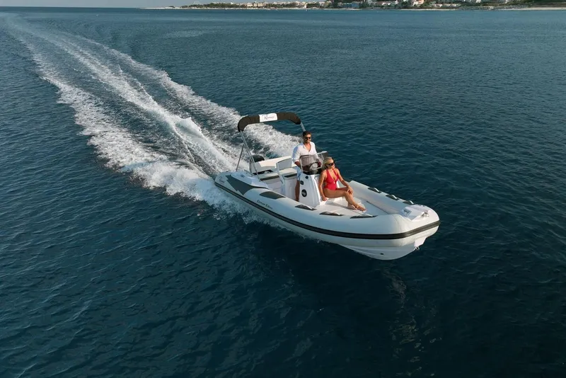The Image of 2026 Ranieri CAYMAN 19 Sport boat cruising on open water, two passengers enjoying the ride. - 1