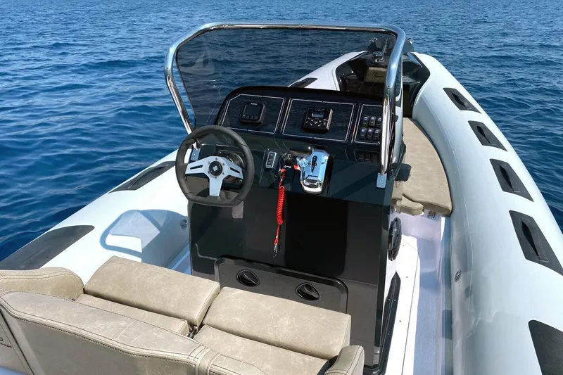 Slide: The Image of 2026 Ranieri Cayman 23.0 Sport boat interior with steering wheel and controls on open water. - 8