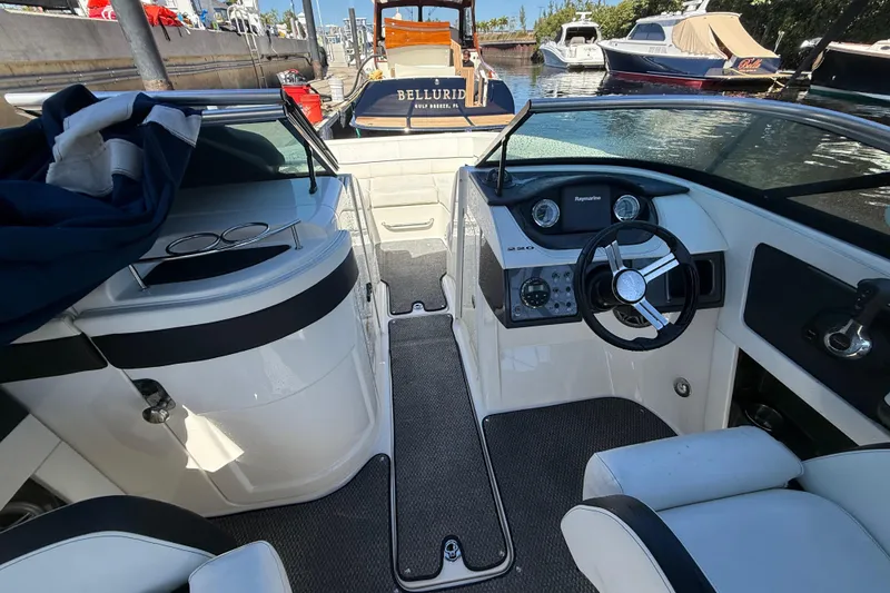 Slide: The Image of 2014 Sea Ray 220 Sundeck interior with steering wheel and dashboard, docked at marina. - 11