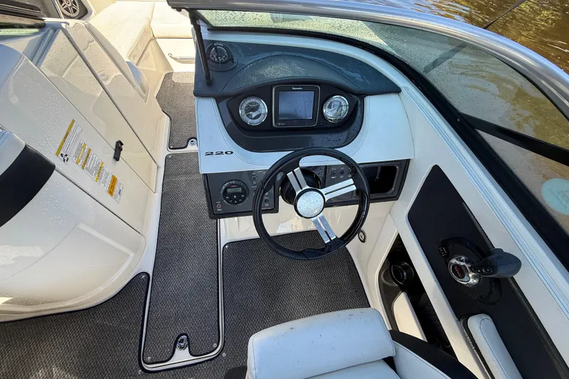 Slide: The Image of 2014 Sea Ray 220 Sundeck boat interior with steering wheel and dashboard controls. - 12