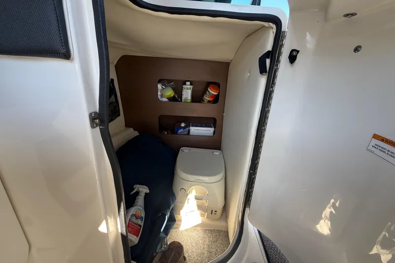 Slide: The Image of Interior of 2014 Sea Ray 220 Sundeck boat with compact toilet and storage shelves. - 18