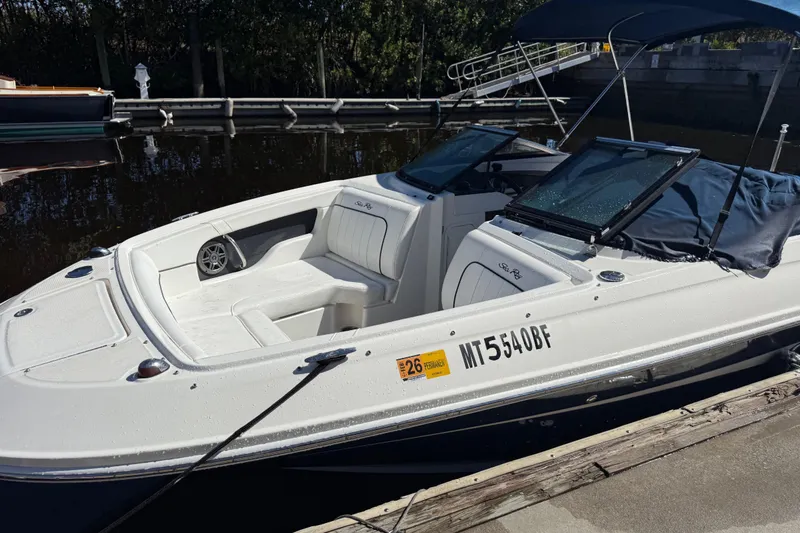 Slide: The Image of 2014 Sea Ray 220 Sundeck boat docked, featuring white seating and a sleek design. - 2