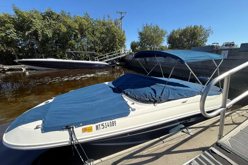 Slide: The Image of 2014 Sea Ray 220 Sundeck boat docked with blue cover and canopy. - 22