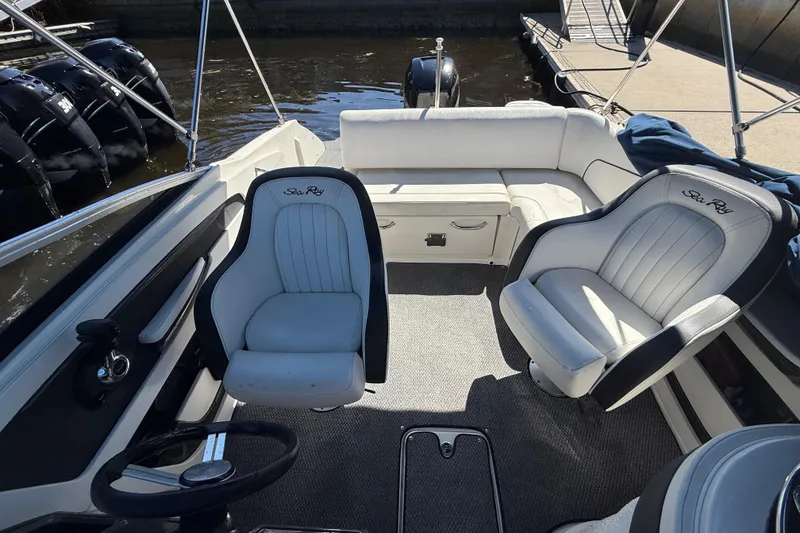 Slide: The Image of 2014 Sea Ray 220 Sundeck interior with seating and steering wheel, docked by water. - 9