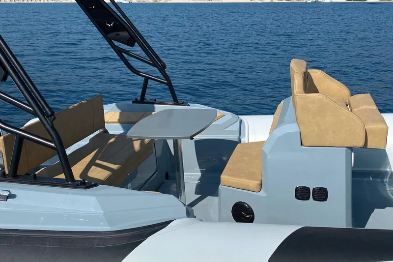 Slide: The Image of 2026 Ranieri Cayman 26.0 Sport boat interior with seating and table on calm water. - 2