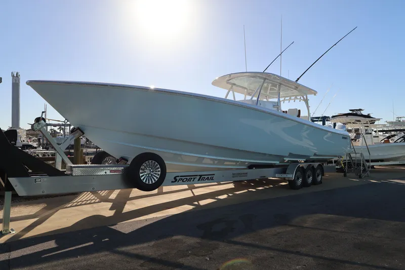Slide: The Image of 2026 Contender 44 CB boat on trailer under bright sun, surrounded by palm trees. - 2
