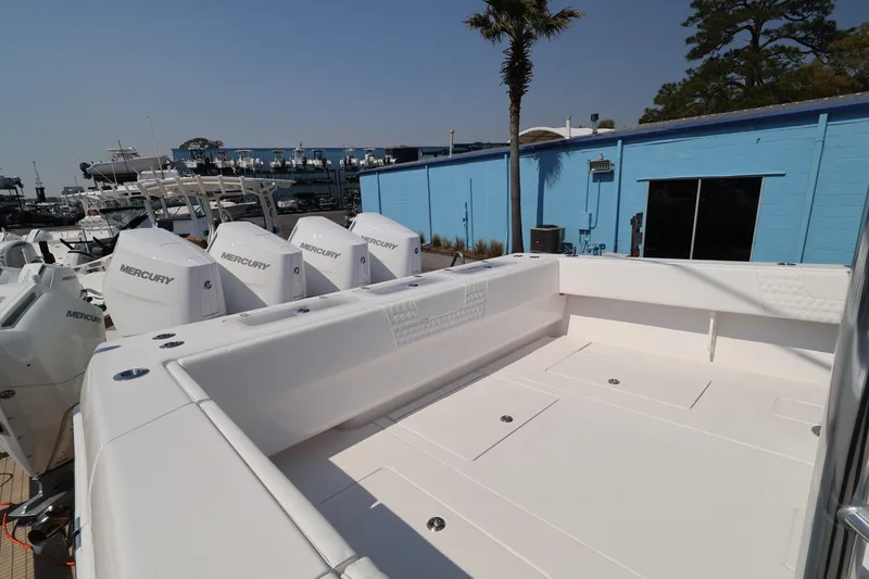 Slide: The Image of 2026 Contender 44 CB boat with Mercury engines, docked near a blue building. - 41