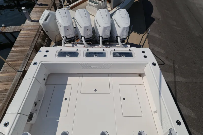 Slide: The Image of 2026 Contender 44 CB boat with four Mercury engines docked at a marina. - 49