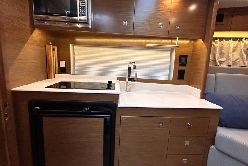 Slide: The Image of 2015 Cruisers Yachts 390 Express Coupe kitchen with modern appliances and sleek wood cabinetry. - 28