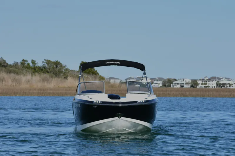 The Image of 2017 Chaparral 230 Suncoast boat cruising on a calm lake with scenic background. - 0