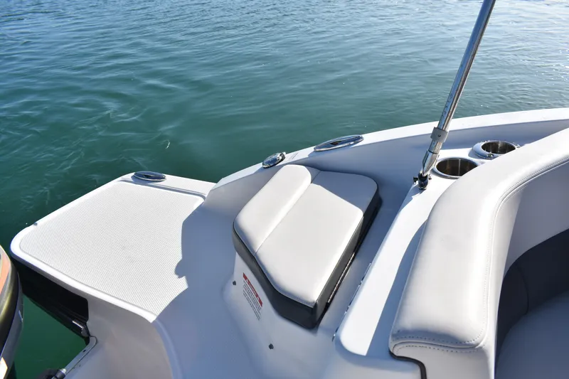 Slide: The Image of 2017 Chaparral 230 Suncoast boat interior with cushioned seating and cup holders on calm water. - 14