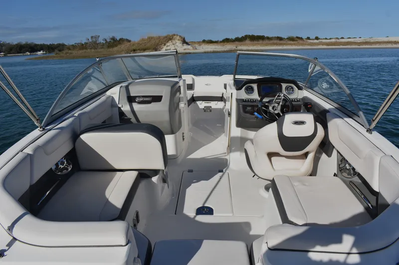 Slide: The Image of 2017 Chaparral 230 Suncoast boat interior with seating and steering wheel on calm water. - 18