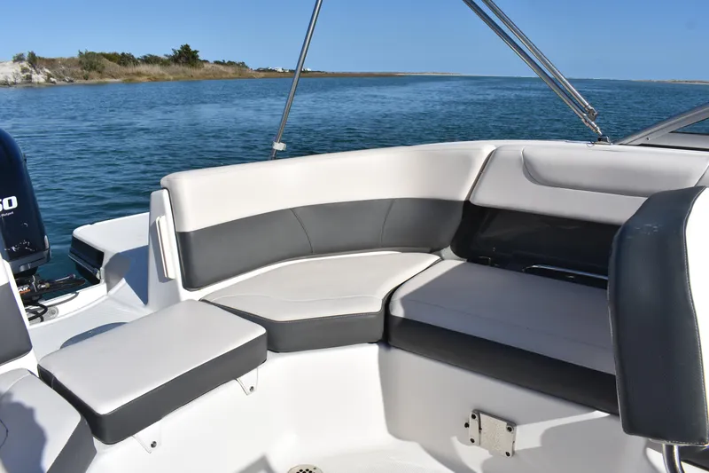 Slide: The Image of 2017 Chaparral 230 Suncoast boat interior with cushioned seating on calm water. - 9