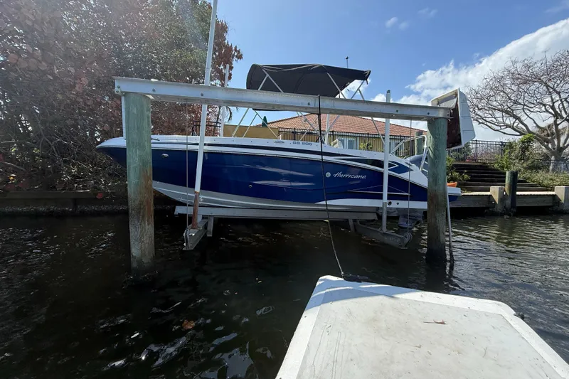 Slide: The Image of 2023 Hurricane SunDeck Sport 205 OB boat docked on a lift by the water. - 6