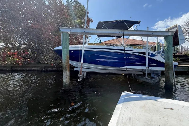 Slide: The Image of 2023 Hurricane SunDeck Sport 205 OB boat docked on a lift by the water. - 7